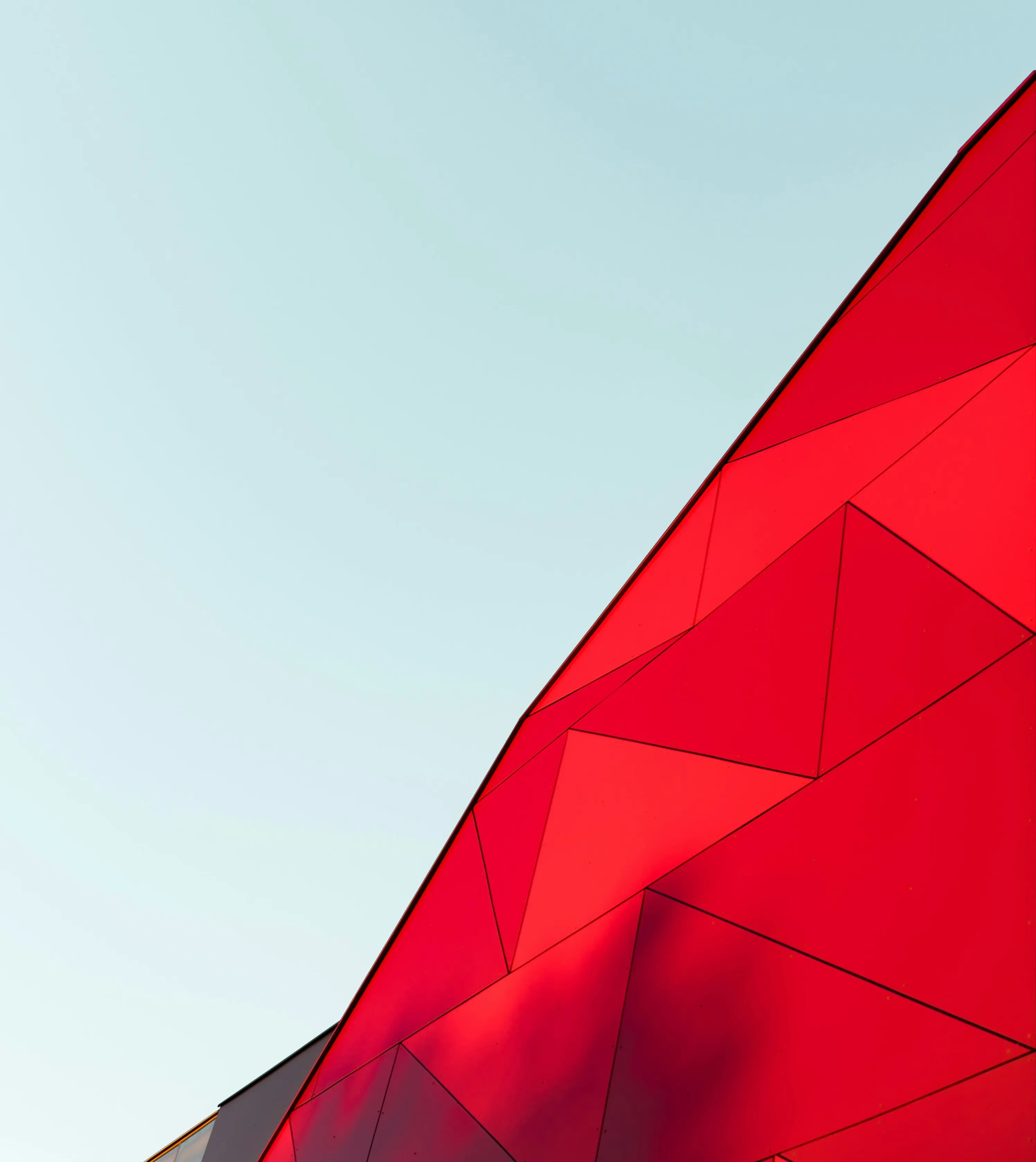 Angular red geometric building against a pale blue sky